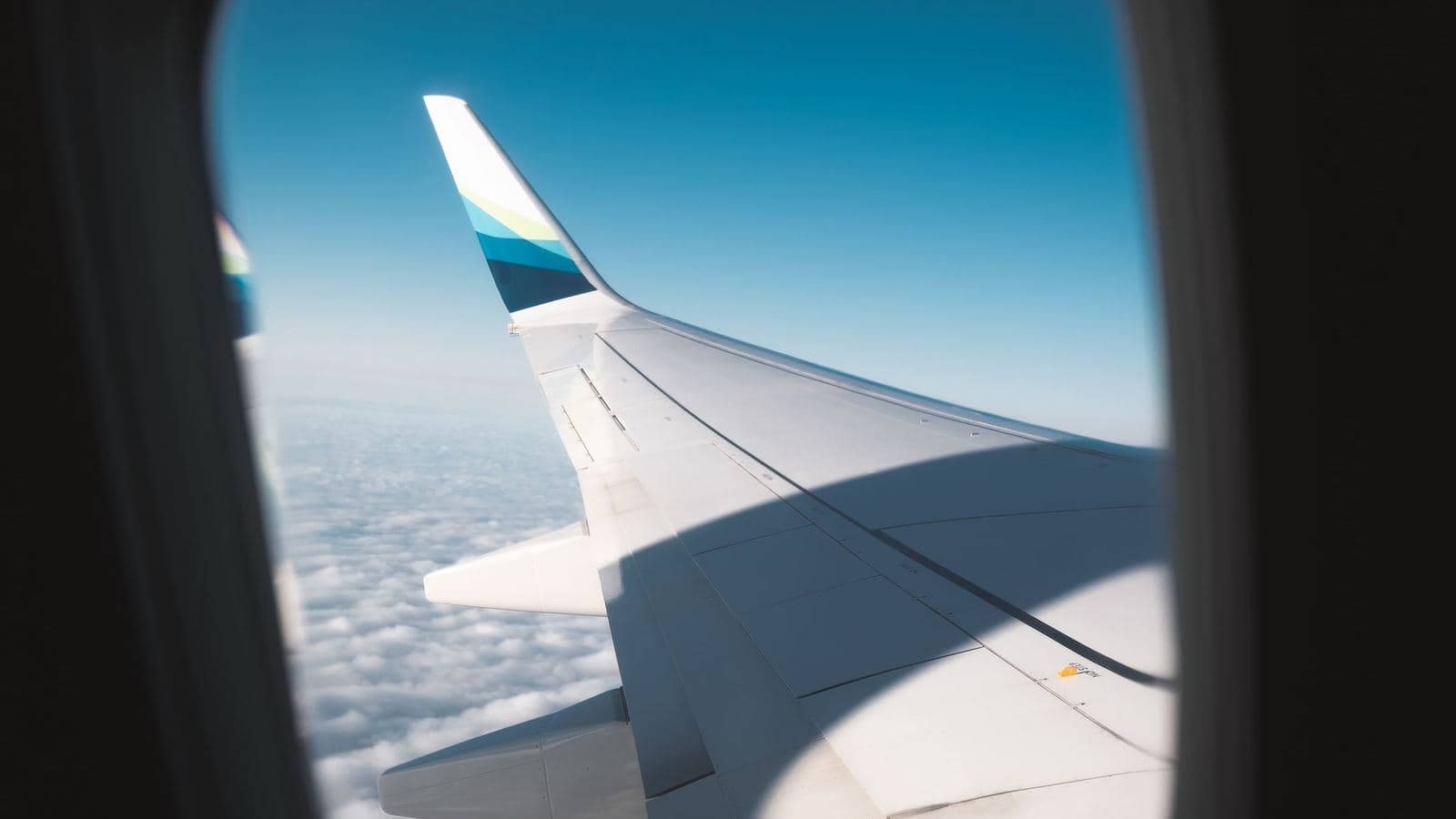 An airplane wing above the clouds at sunrise