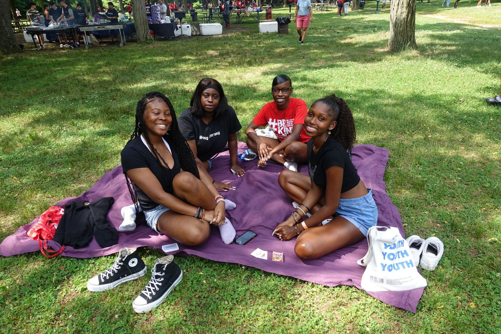 Four friends sitting on a purple picnic blanket