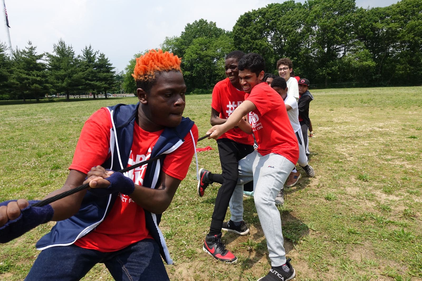 Students in red Richmond Tours shirts pulling hard in a tug of war