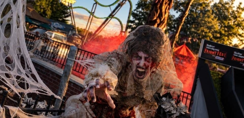 A Fright Fest zombie in front of a roller coaster